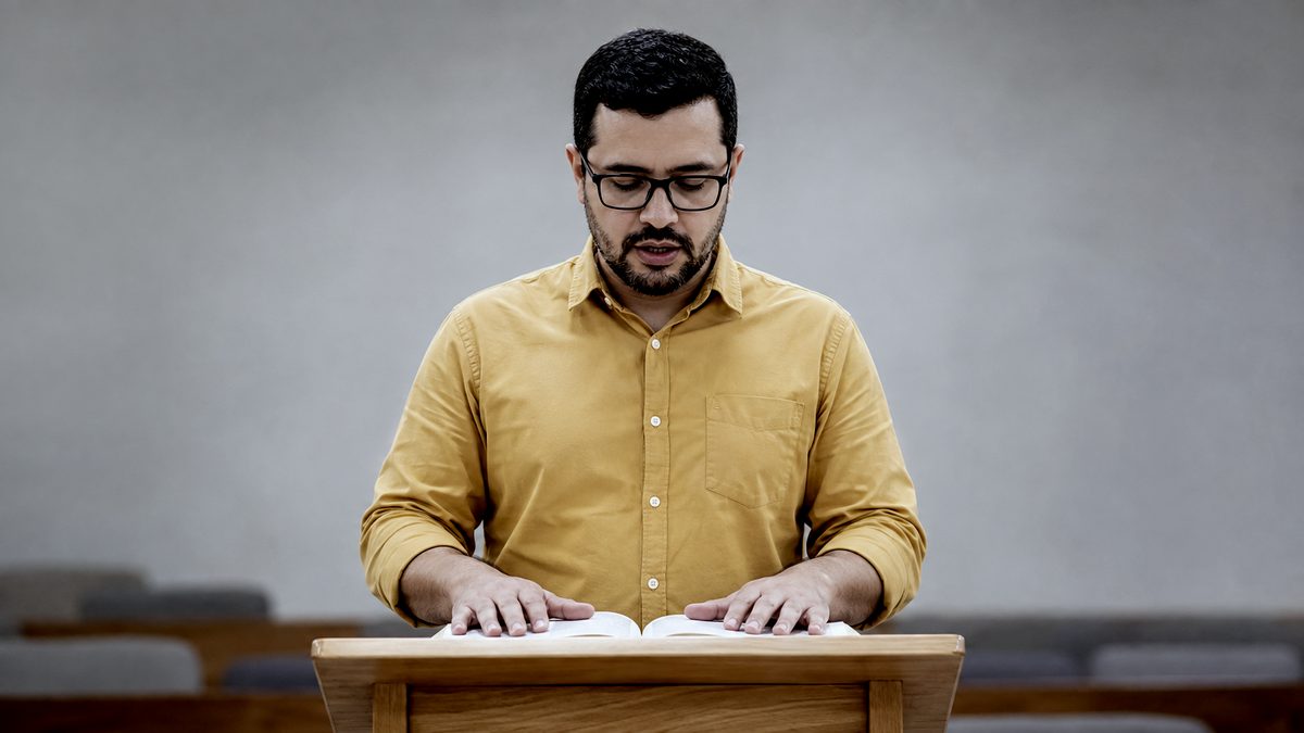 Dirigente Lendo a Bíblia no Púlpito Durante o Culto de Ensino